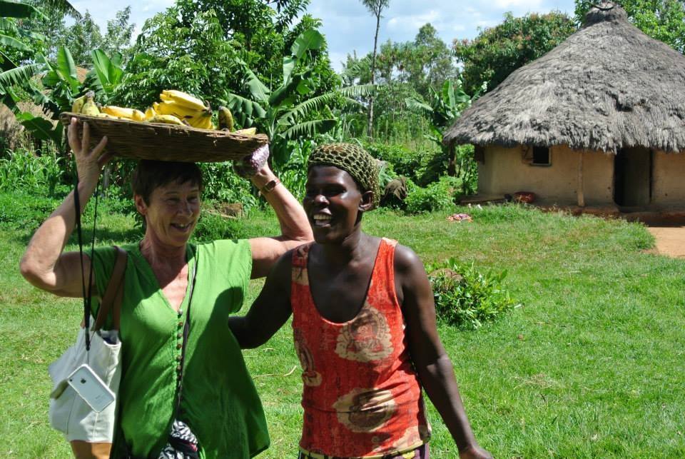 Volunteer and community member carrying bananas on a farm